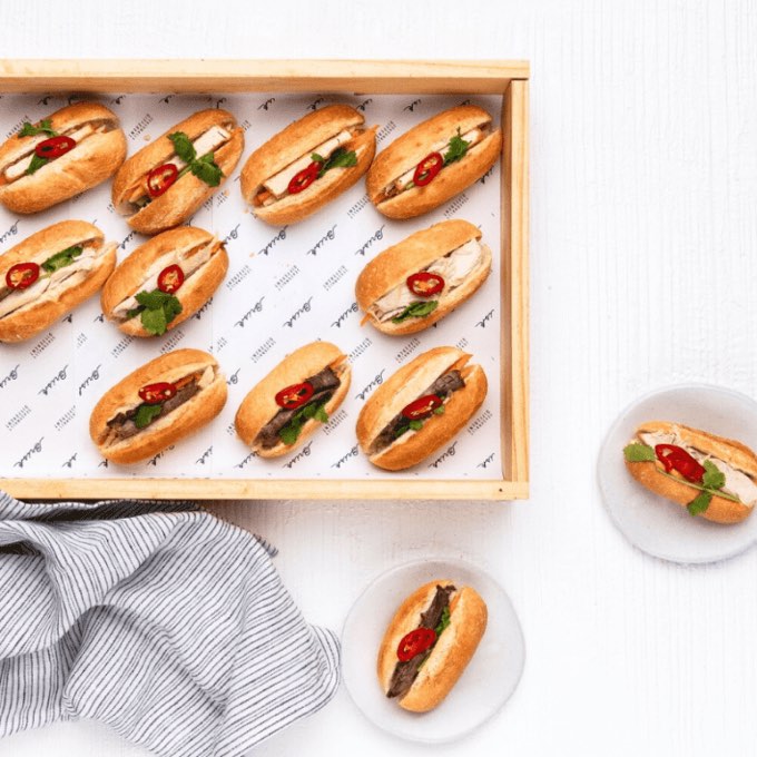 Trays of mini banh mi rolls prepared for an office lunch